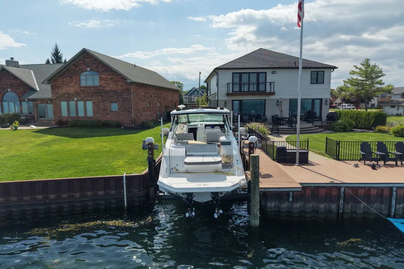 Slide: The Image of 2025 Sea Ray Sundancer 320 docked by waterfront homes under a partly cloudy sky. - 3