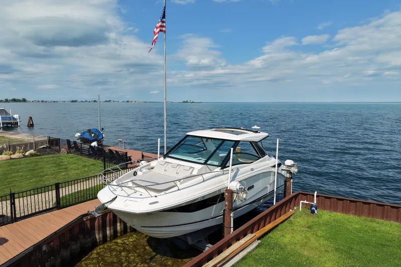 Slide: The Image of 2025 Sea Ray Sundancer 320 docked by a serene lake under a blue sky. - 5