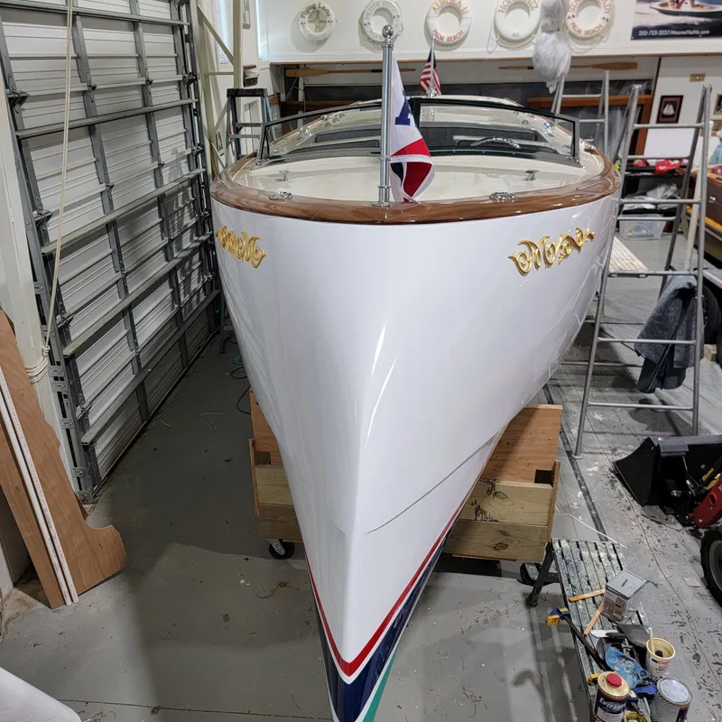 Slide: The Image of Custom M27 boat, 2023 model, in a garage with decorative gold accents and a flag. - 9