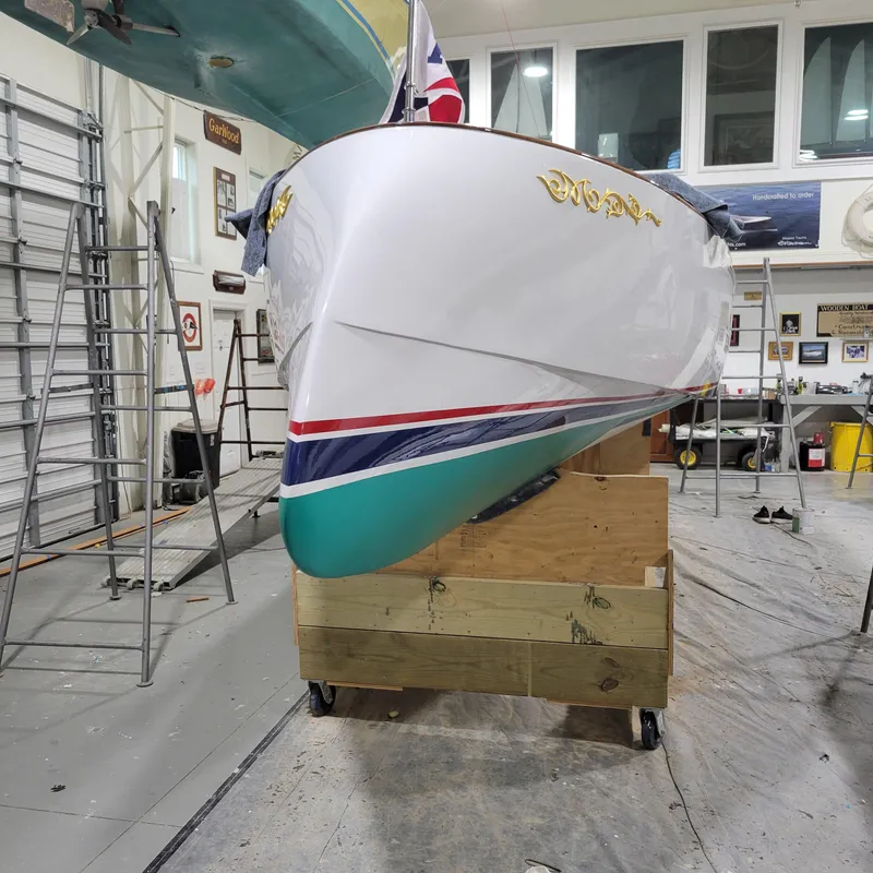 Slide: The Image of Custom M27 boat in workshop, 2023 model, with vibrant hull colors and gold lettering. - 11
