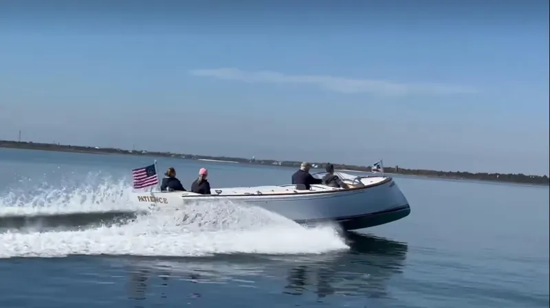 Slide: The Image of Custom M27 boat cruising on calm water, 2023 model, with passengers and an American flag. - 0