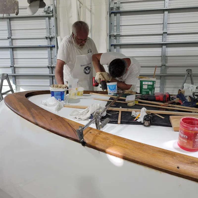 Slide: The Image of Two people working on a boat restoration project in a garage. - 15