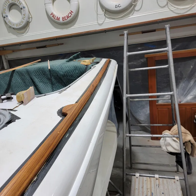 Slide: The Image of Custom M27 boat under maintenance with wooden trim, ladder, and life rings in a workshop. - 16
