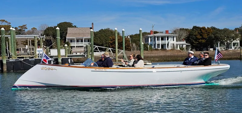 The Image of Custom M27 boat cruising on a sunny day near waterfront homes, 2023 model. - 2
