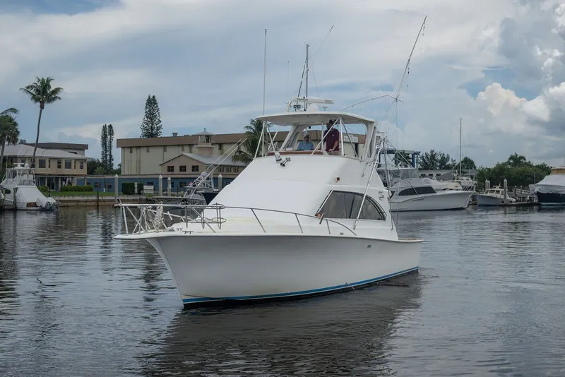 The Image of 1997 Ocean Yachts 40 Super Sport cruising in a marina with palm trees and buildings. - 0