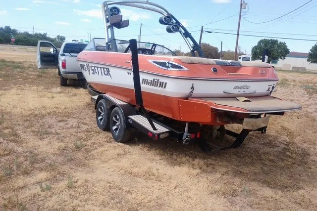 Slide: The Image of 2013 Malibu Wakesetter 23 LSV boat on trailer, parked on grassy field. - 15
