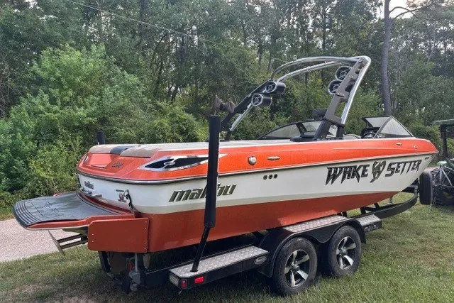Slide: The Image of 2013 Malibu Wakesetter 23 LSV boat on trailer, surrounded by trees. - 2