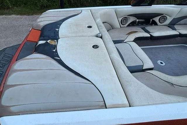 Slide: The Image of 2013 Malibu Wakesetter 23 LSV boat interior with worn upholstery and seating area. - 8