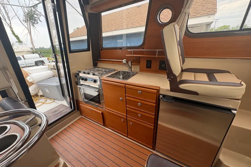 Slide: The Image of 2018 Ranger Tugs R-27 interior with kitchenette, stove, sink, and seating. - 13