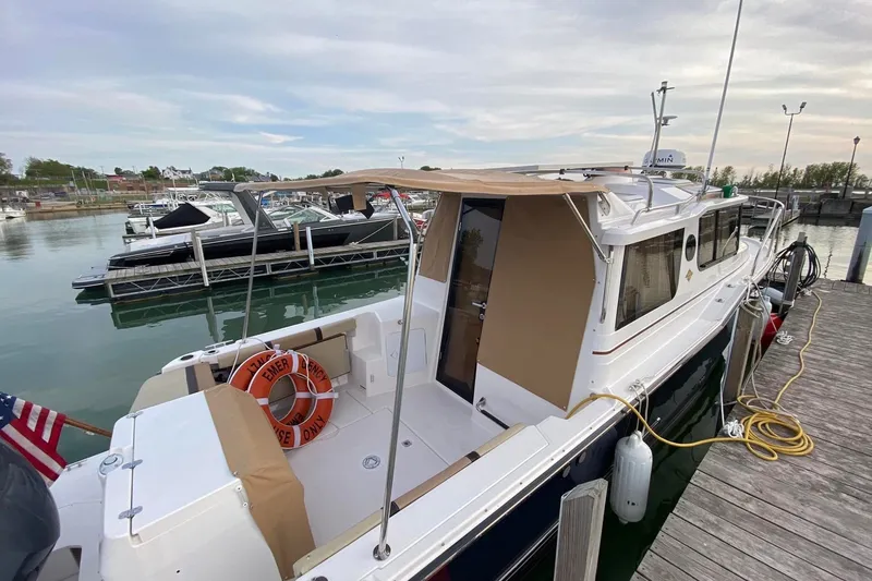 The Image of 2018 Ranger Tugs R-27 docked at marina, featuring spacious deck and canopy. - 5