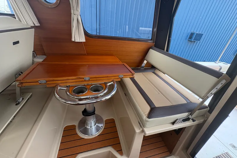 Slide: The Image of 2018 Ranger Tugs R-27 interior with wooden table, cushioned seating, and cup holders. - 17