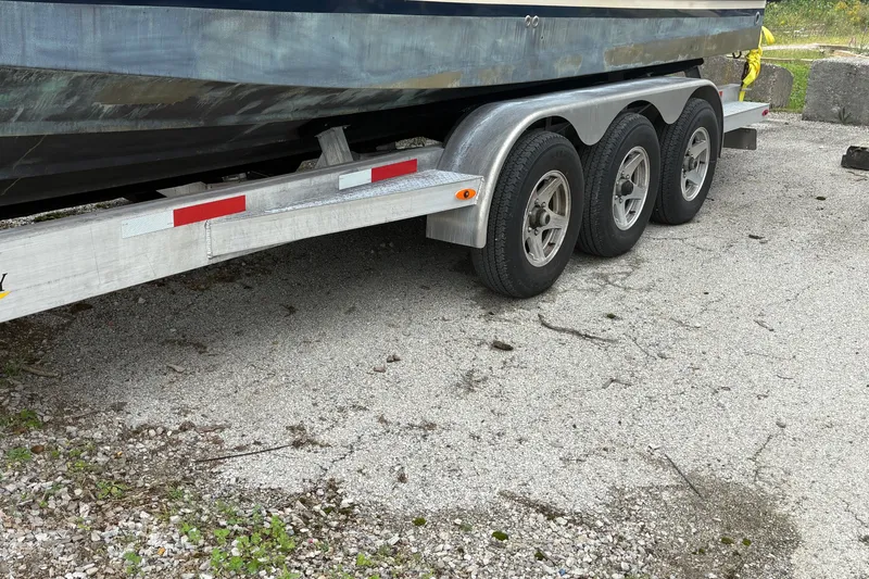 Slide: The Image of 2018 Ranger Tugs R-27 boat on a triple-axle trailer, parked on gravel. - 11