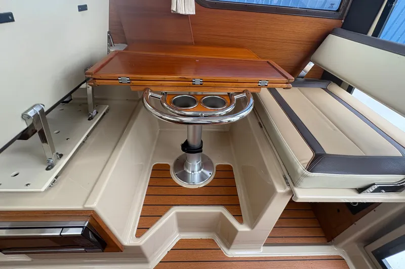Slide: The Image of 2018 Ranger Tugs R-27 interior with wooden table, seating, and cup holders. - 16