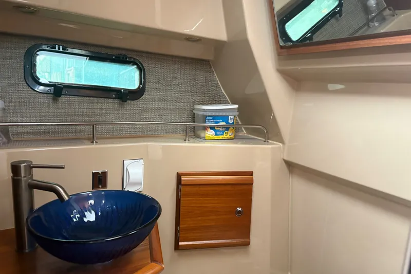 Slide: The Image of 2018 Ranger Tugs R-27 interior with blue sink, wooden cabinet, and porthole window. - 26