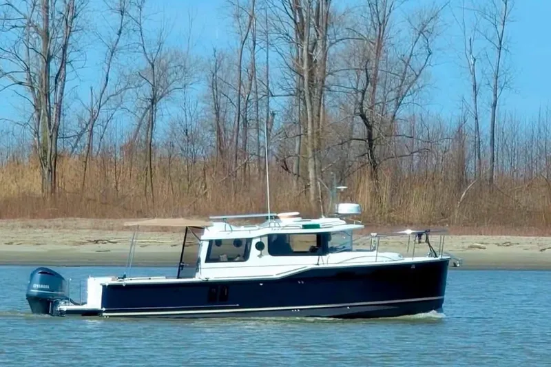 Slide: The Image of 2018 Ranger Tugs R-27 boat cruising on a calm river near a wooded shoreline. - 26