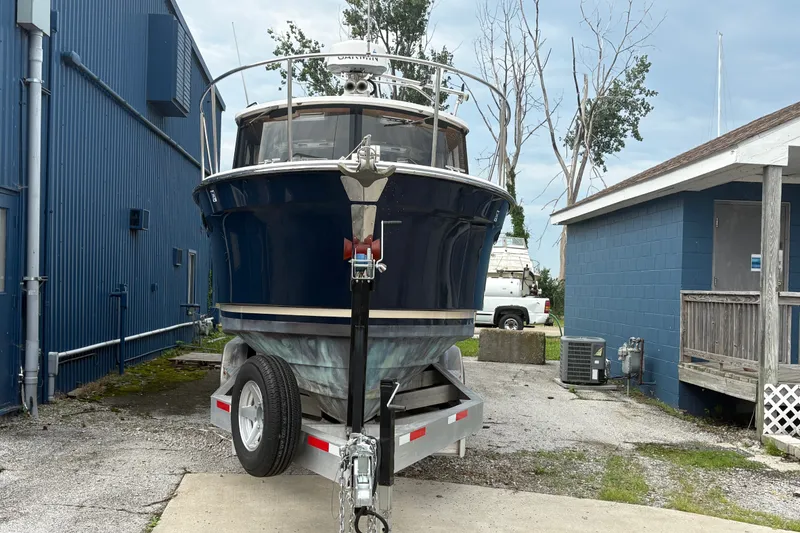 Slide: The Image of 2018 Ranger Tugs R-27 boat on trailer, parked near blue buildings. - 3
