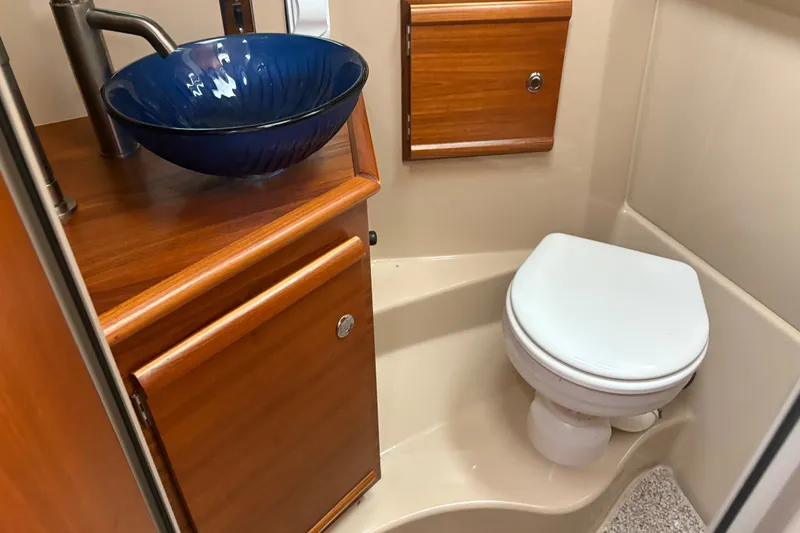 Slide: The Image of 2018 Ranger Tugs R-27 bathroom with blue vessel sink and wooden cabinetry. - 27