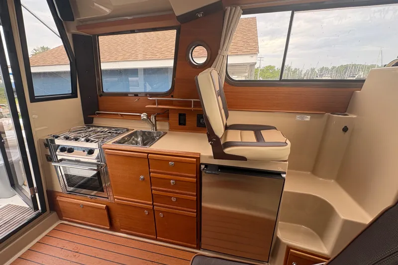 Slide: The Image of Interior of 2018 Ranger Tugs R-27 boat featuring kitchen and seating area. - 14