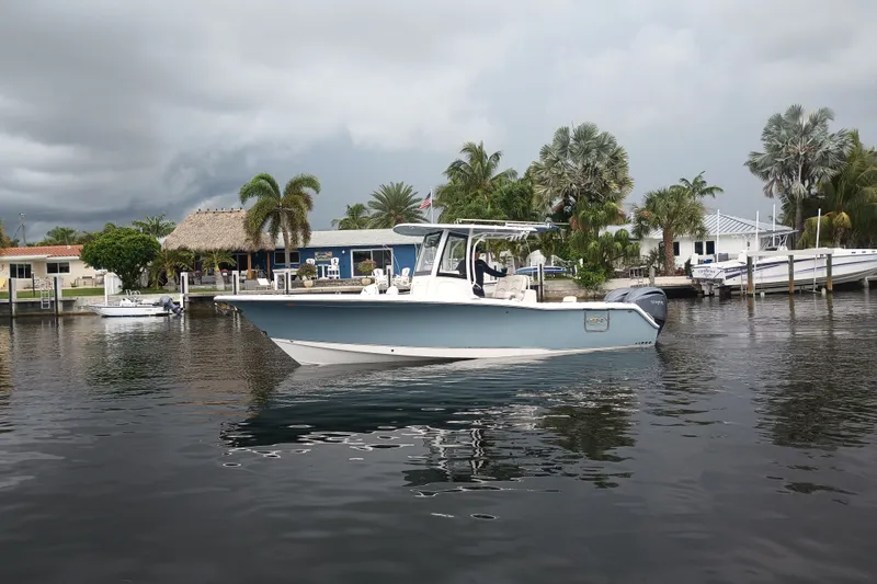 Slide: The Image of 2021 Sea Hunt Gamefish 27FS boat on calm water near tropical waterfront homes. - 39