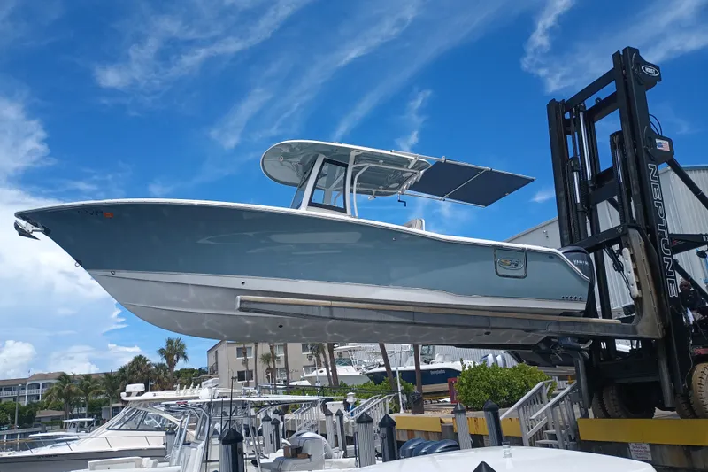 Slide: The Image of 2021 Sea Hunt Gamefish 27FS boat on forklift under clear blue sky. - 0