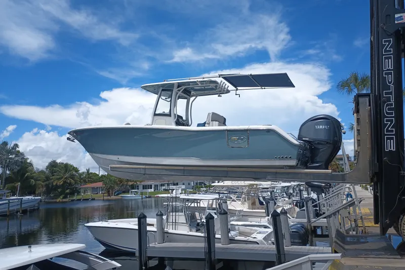 Slide: The Image of 2021 Sea Hunt Gamefish 27FS boat lifted at marina, clear sky background. - 1
