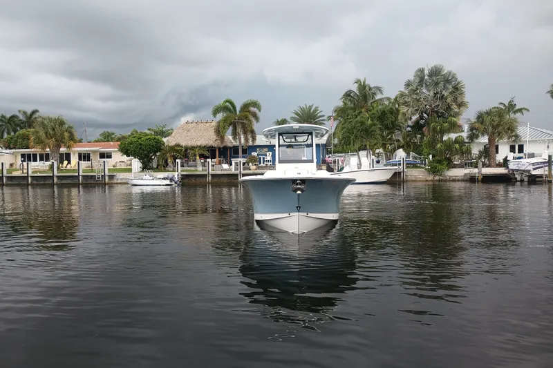 Slide: The Image of 2021 Sea Hunt Gamefish 27FS boat on calm water, with tropical waterfront homes in the background. - 36