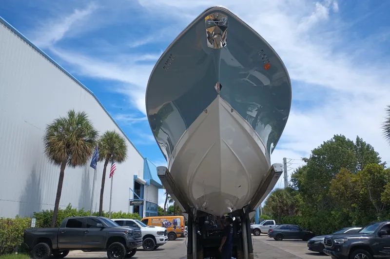 Slide: The Image of 2021 Sea Hunt Gamefish 27FS boat displayed outdoors, surrounded by palm trees and vehicles. - 2