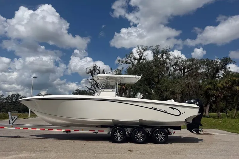 The Image of 2006 Fountain 32 Center Console boat on trailer under blue sky. - 0