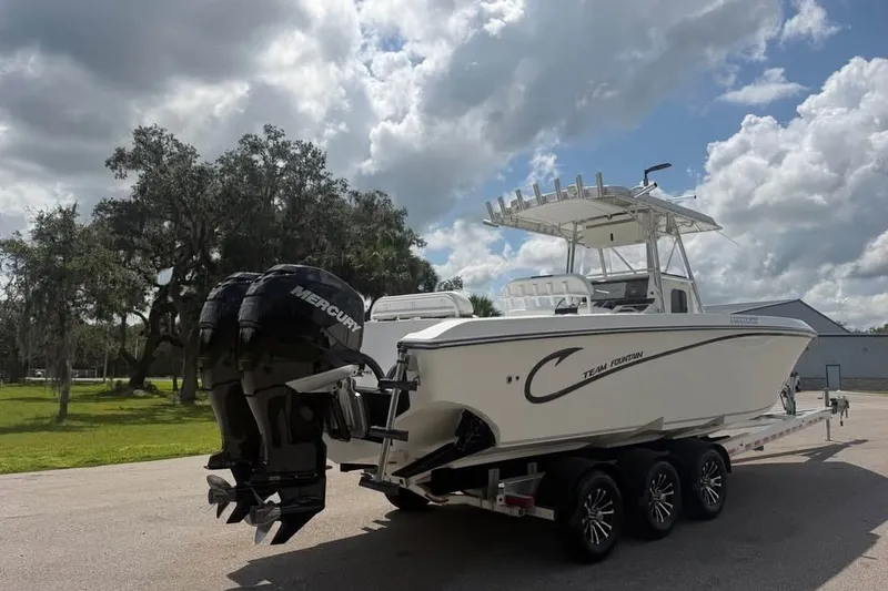 Slide: The Image of 2006 Fountain 32 Center Console boat on trailer with dual Mercury engines, under cloudy sky. - 5