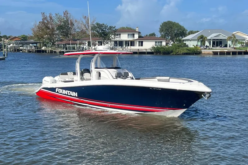 Slide: The Image of 2021 Fountain 39 NX boat cruising on a sunny day near waterfront homes. - 9
