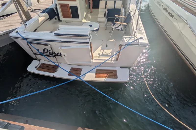 Slide: The Image of 1988 Tiara 33 Express boat docked, featuring a spacious deck and seating area. - 5