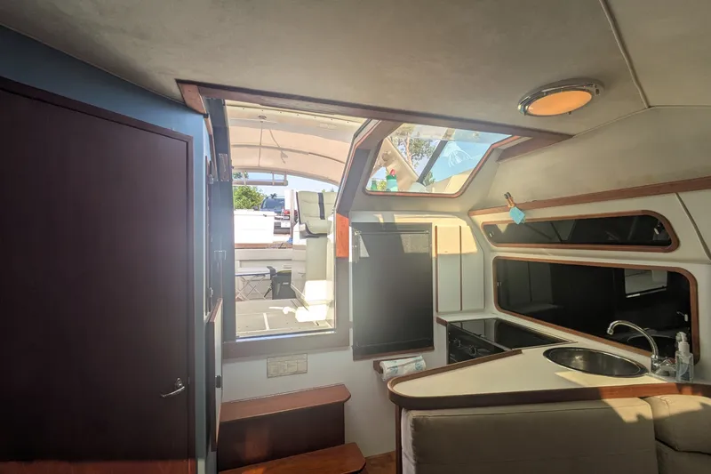 Slide: The Image of Interior of a 1988 Tiara 33 Express boat, featuring a compact kitchen and seating area. - 11