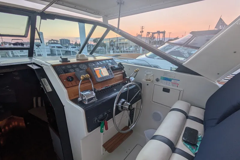 Slide: The Image of 1988 Tiara 33 Express boat cockpit with steering wheel and navigation equipment at sunset. - 4