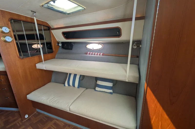 Slide: The Image of Interior of 1988 Tiara 33 Express boat with cozy bunk beds and nautical decor. - 16
