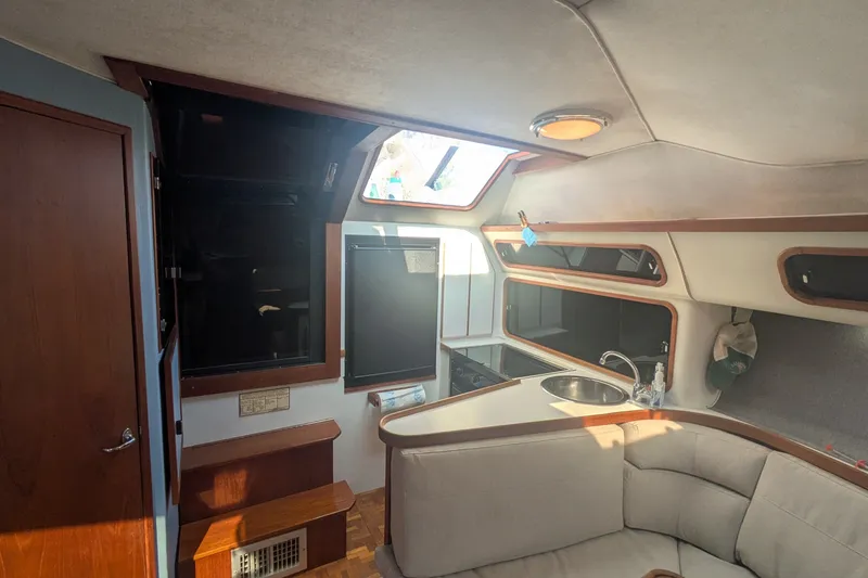 Slide: The Image of Interior of a 1988 Tiara 33 Express boat, featuring a cozy seating area and compact kitchen. - 12