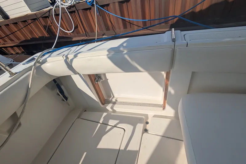Slide: The Image of 1988 Tiara 33 Express boat interior with white seating and deck, featuring ropes and wooden accents. - 9