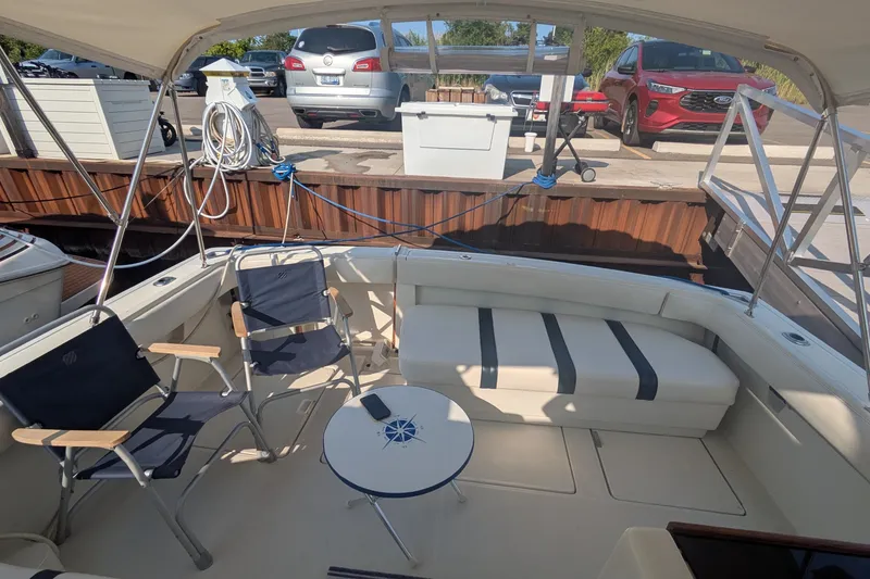 Slide: The Image of 1988 Tiara 33 Express boat interior with seating and table, docked near parked cars. - 7