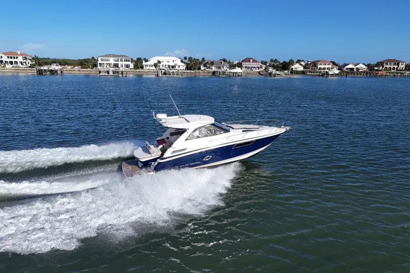 Slide: The Image of 2016 Regal 35 Sport Coupe cruising on a sunny day near waterfront homes. - 11