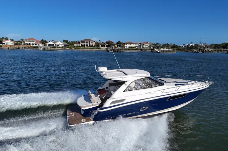 Slide: The Image of 2016 Regal 35 Sport Coupe cruising on a sunny day near waterfront homes. - 2