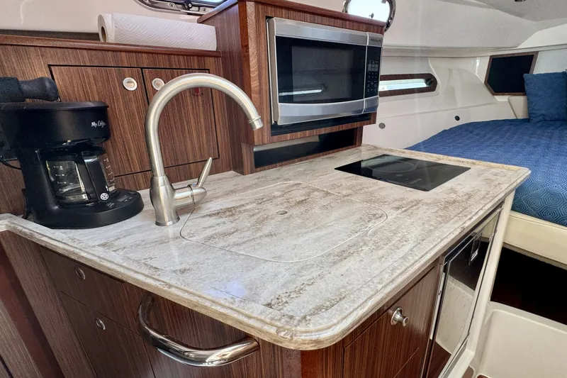 Slide: The Image of 2017 Pursuit OS 325 Offshore boat kitchen with sink, microwave, and coffee maker. - 19