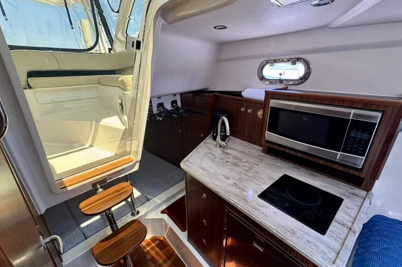 Slide: The Image of 2017 Pursuit OS 325 Offshore cabin with kitchenette, featuring microwave and sink. - 18