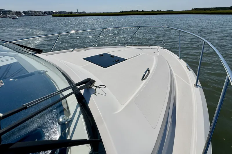 Slide: The Image of 2017 Pursuit OS 325 Offshore boat on water, showcasing sleek deck design and railing. - 16