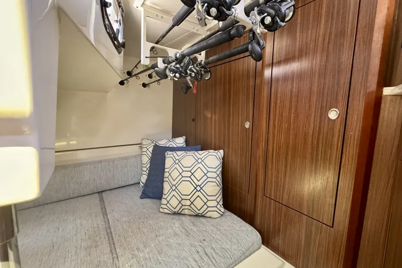 Slide: The Image of 2017 Pursuit OS 325 Offshore cabin with fishing rods and cozy seating area. - 26