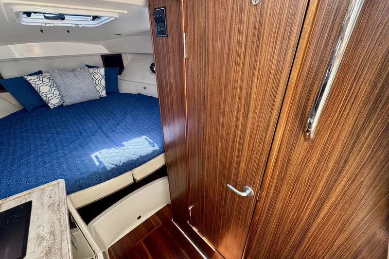 Slide: The Image of 2017 Pursuit OS 325 Offshore cabin interior with wood paneling and cozy bed. - 23