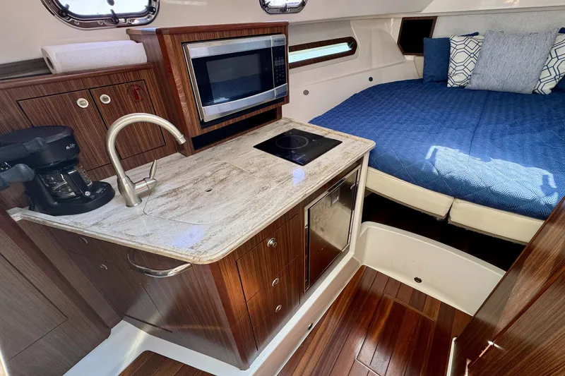 Slide: The Image of 2017 Pursuit OS 325 Offshore cabin with kitchenette and cozy sleeping area. - 17