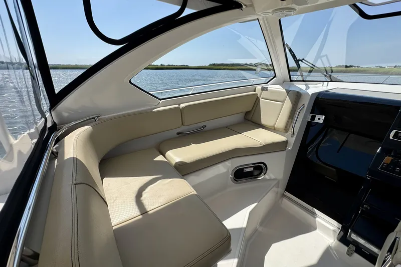 Slide: The Image of 2017 Pursuit OS 325 Offshore boat interior with beige seating and scenic water view. - 9