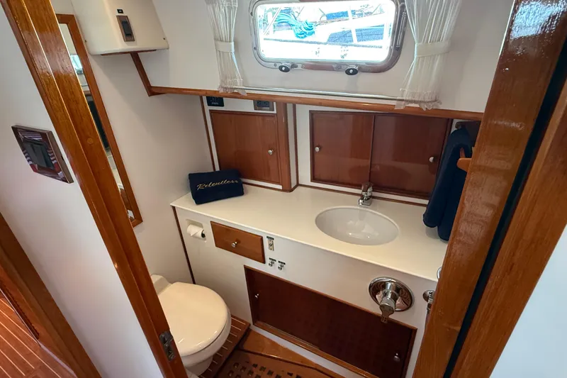 Slide: The Image of Bathroom interior of 2001 Grand Banks 49 Eastbay HX yacht, featuring wooden cabinetry and porthole window. - 47