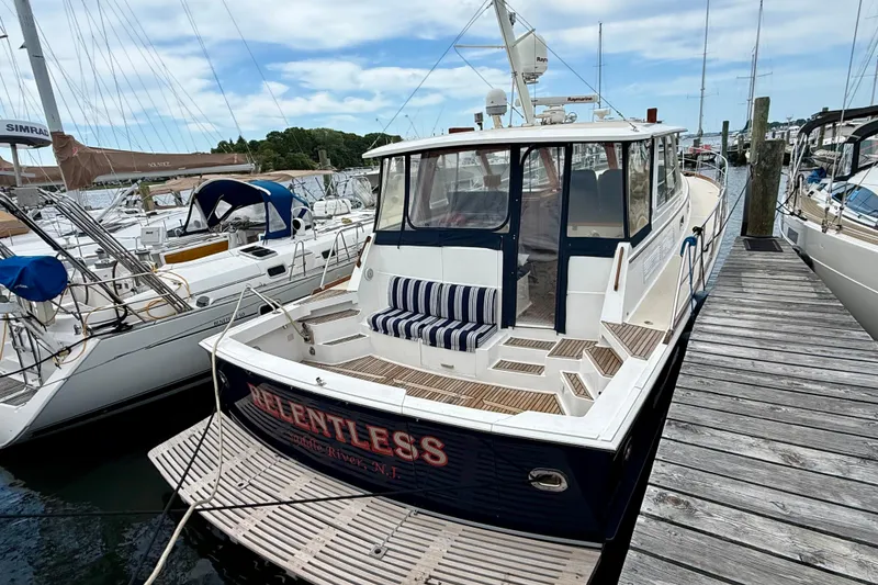 Slide: The Image of 2001 Grand Banks 49 Eastbay HX docked, featuring spacious deck and striped seating. - 14