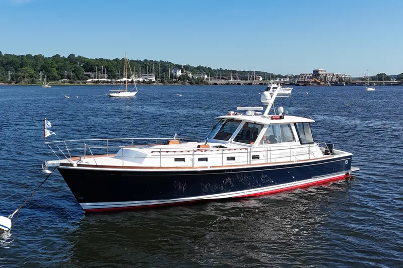 Slide: The Image of 2001 Grand Banks 49 Eastbay HX yacht anchored on a serene lake under a clear blue sky. - 1