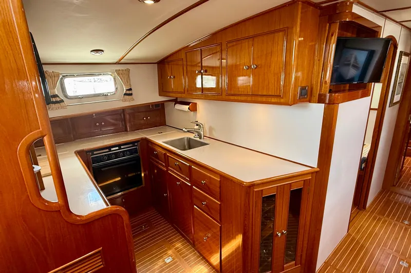 Slide: The Image of Luxurious 2001 Grand Banks 49 Eastbay HX yacht kitchen with wood cabinetry and modern appliances. - 52